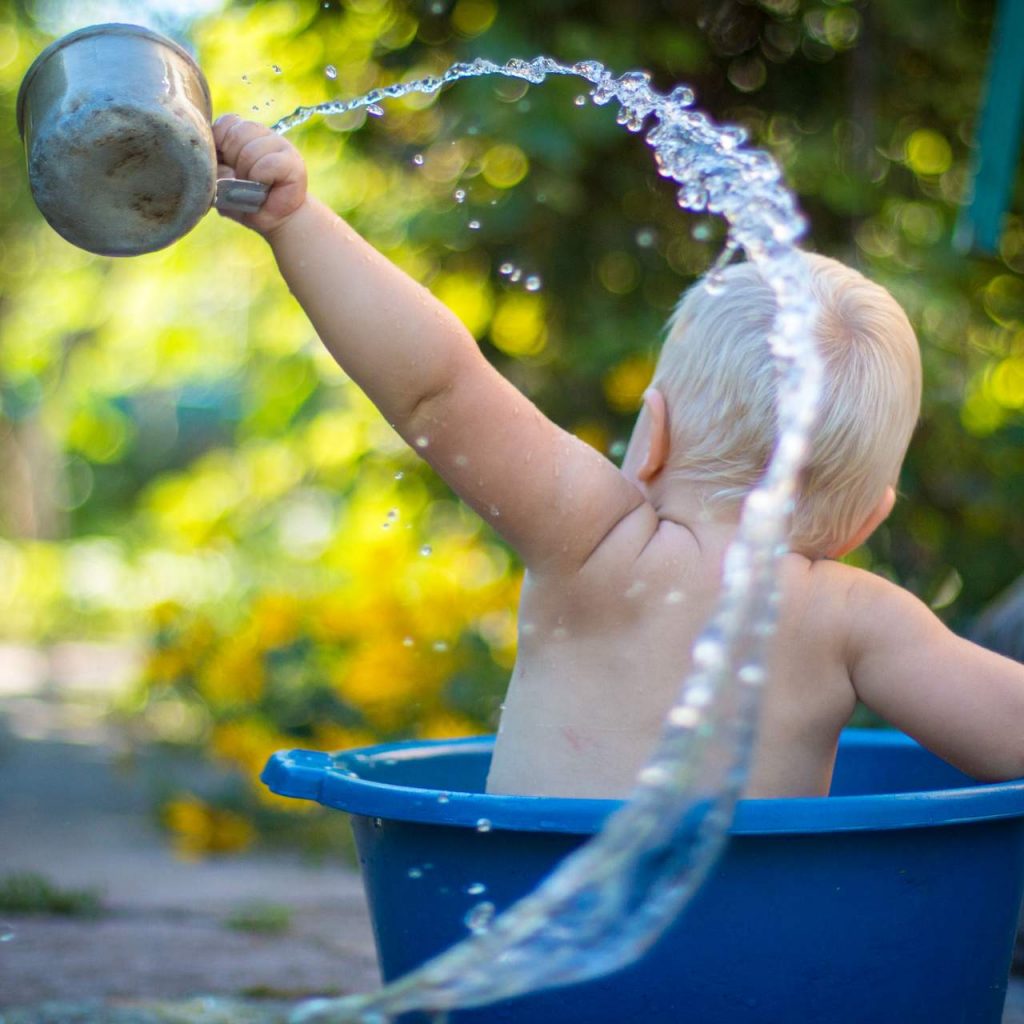 Baby im Wasserbehälter spritzend