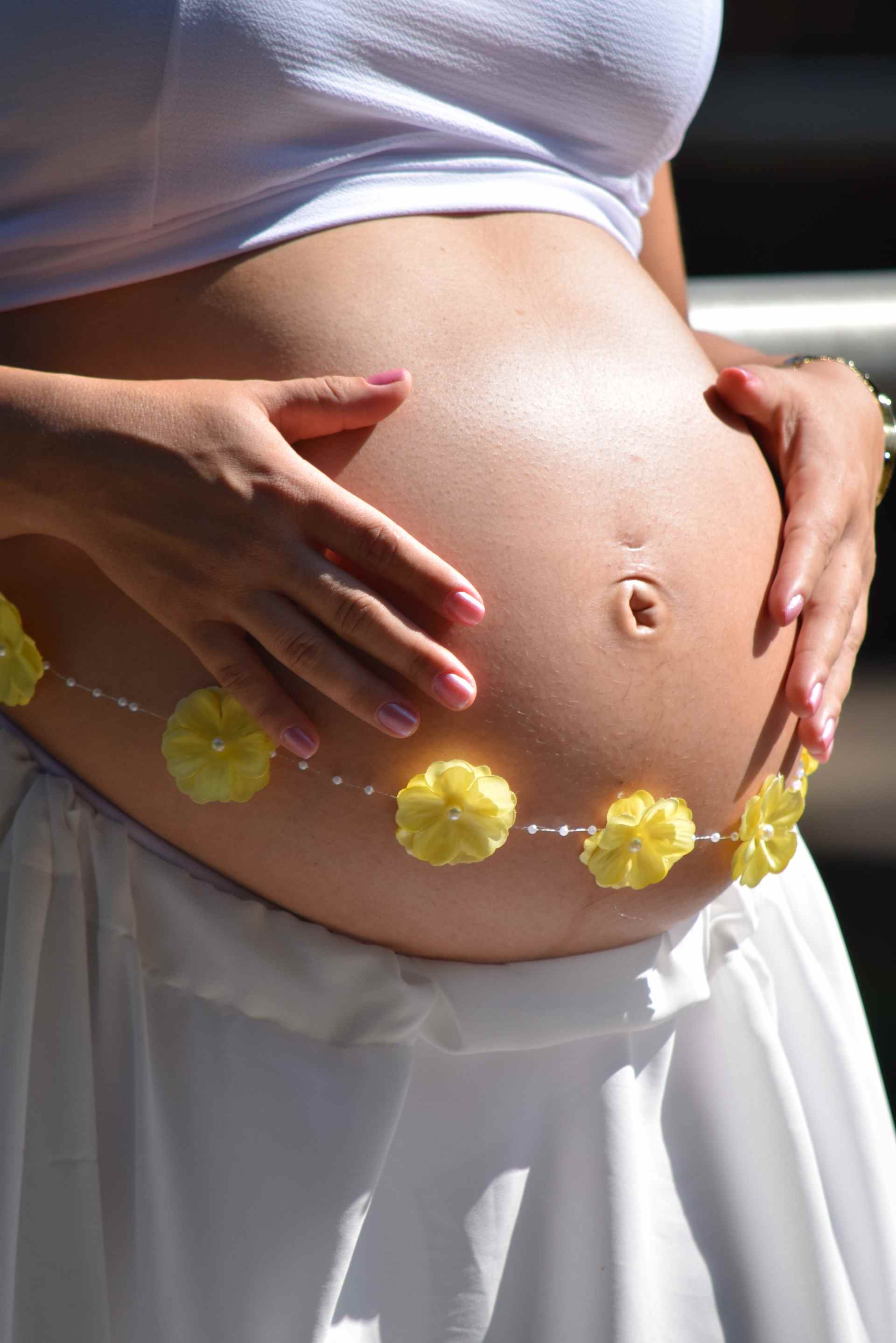 Schwangere Frau mit Blumenkette um Bauch